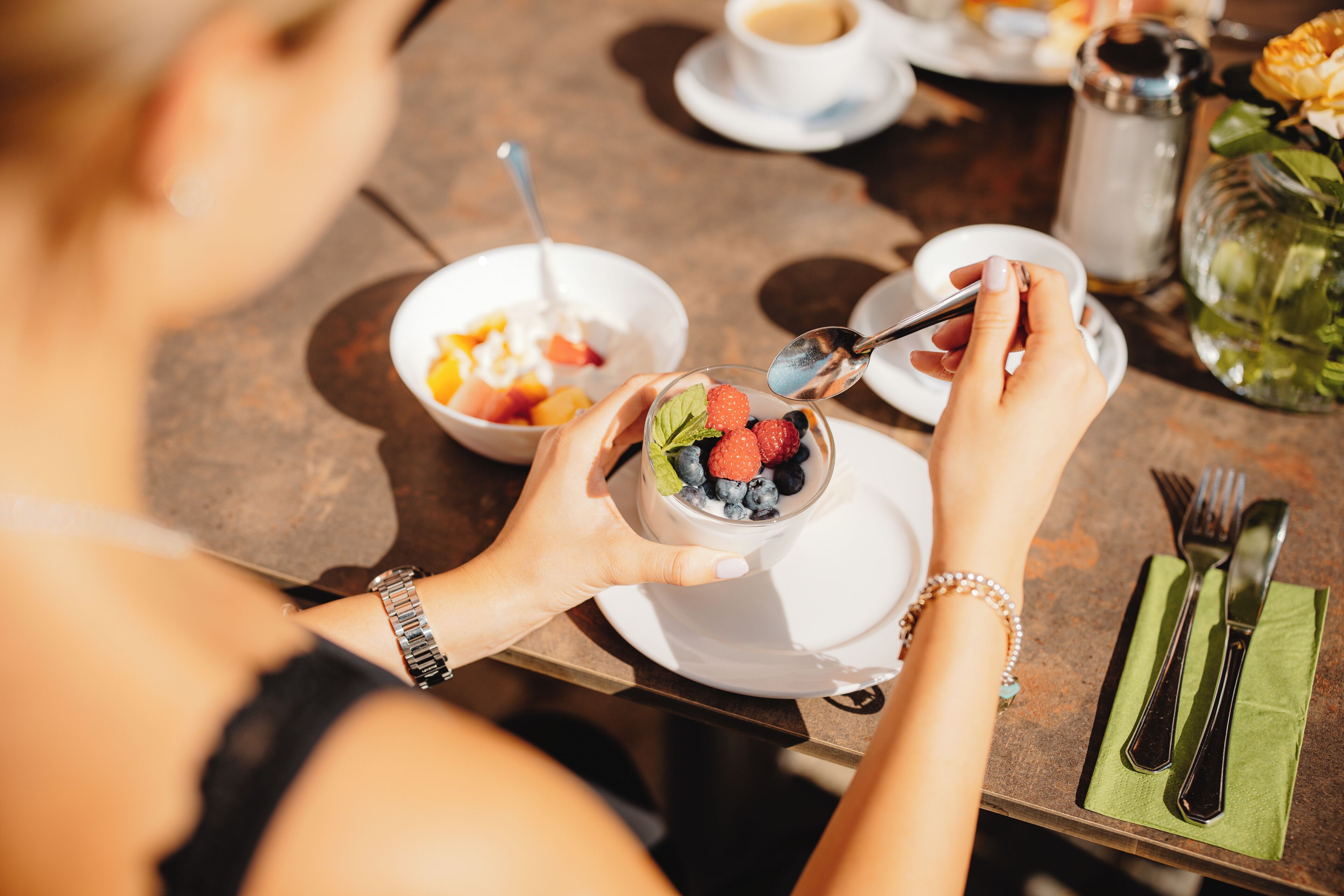 Une table à manger avec un saladier de fruits, une tasse de café et un salier.