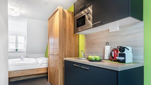Cocina compacta con microondas, hervidor y un lavamanos pequeño.
