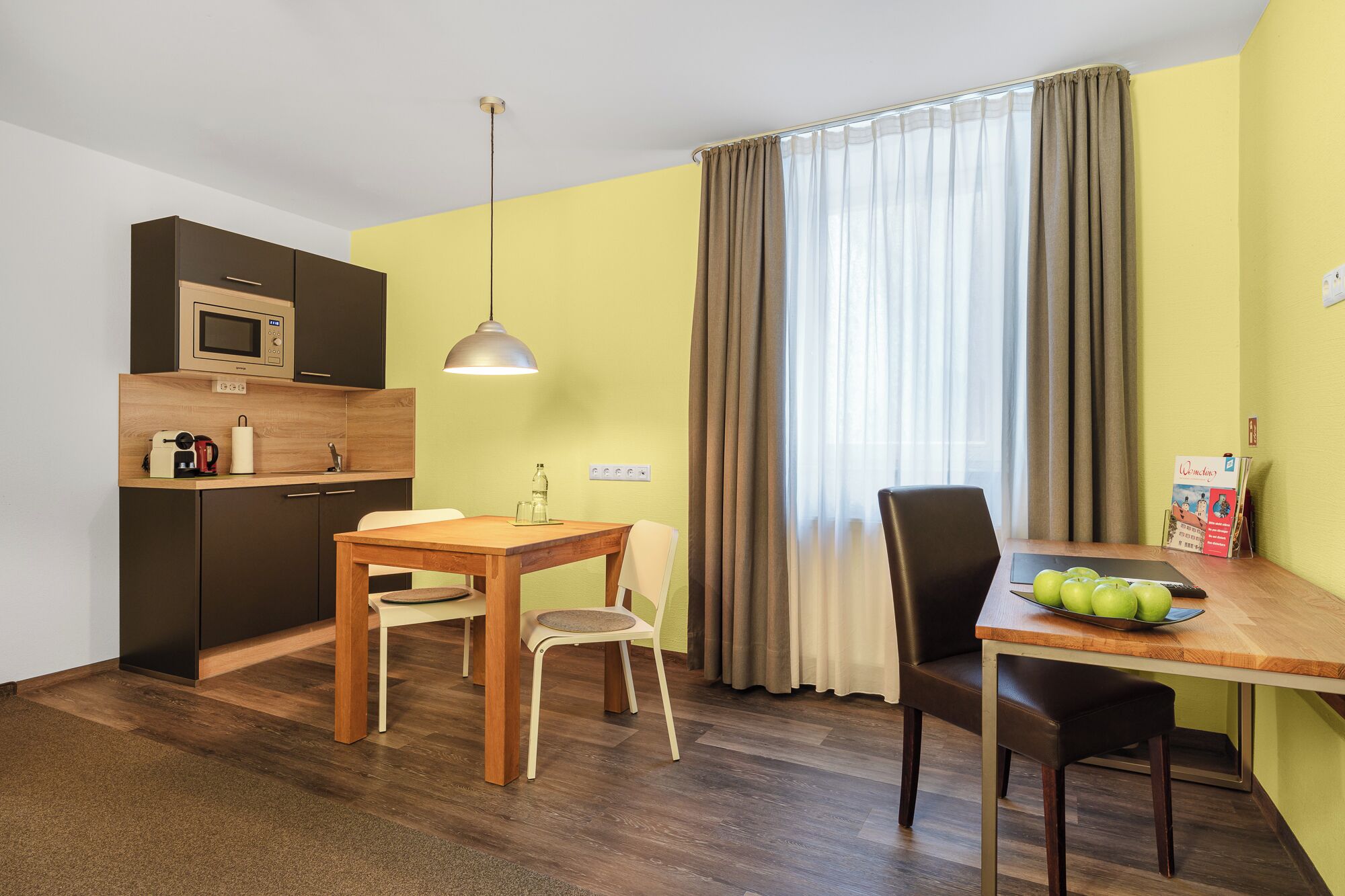 Una cocina compacta con microondas, una mesa de madera y sillas.