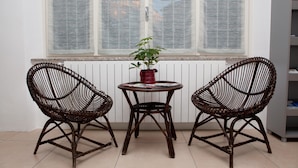 Una habitación con dos sillas de mimbre alrededor de una mesita con una planta en maceta.