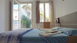 Un dormitorio con cama, una silla, una ventana y un radiador.