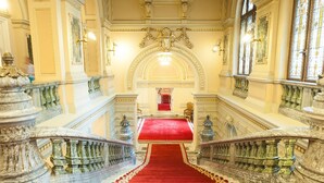 A grand staircase with ornate railings and a red carpet leading to a red-carpeted area. - Grand Pier Boutique Hotel (Bucharest)