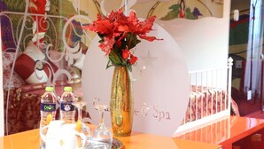 A table with a vase of red flowers, two bottles of water, a teapot, and two glasses. - Grand Pier Boutique Hotel (Bucharest)