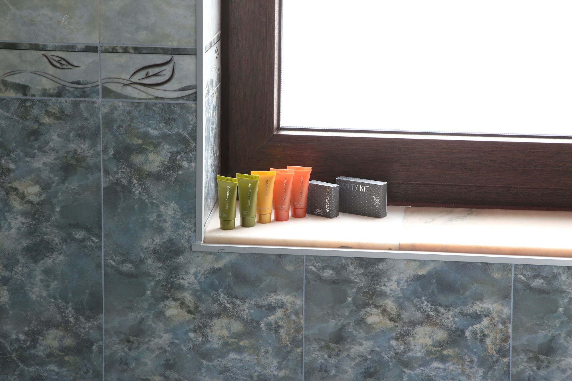A bathroom with a window, a shelf with toiletries, and a shower cap.