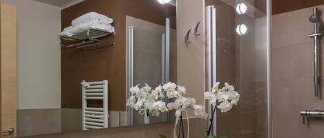 A modern bathroom with a large mirror, white sink, and a shower area.