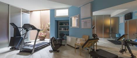 Uma academia em casa com equipamentos de ginástica, esteira, bicicleta ergométrica e banco de musculação.