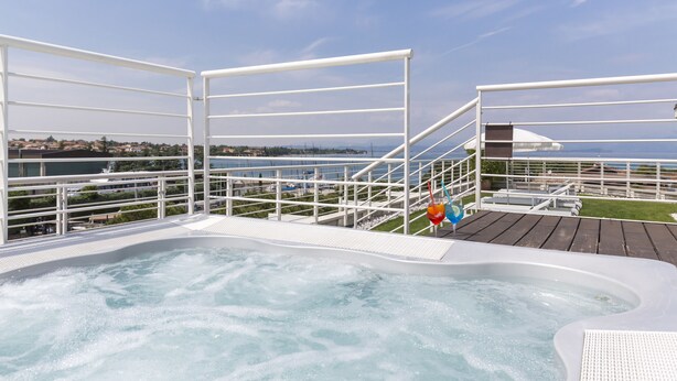 A hot tub area with a view of the sea and a deck with railings. - Hotel Acquadolce (Peschiera del Garda)