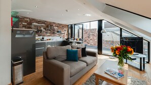 A modern living space with a kitchen, a sofa, and a dining area. - Base Serviced Apartments - Sir Thomas Street (Liverpool)