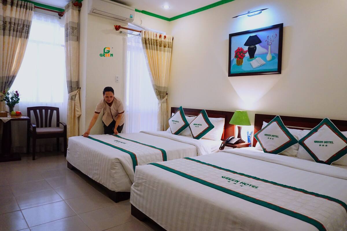 A hotel room with two beds, a chair, a desk, and a window with curtains.