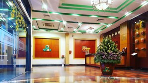 A hotel lobby with a reception desk, a large potted plant, and a wall clock. - Green Hotel (Ho Chi Minh City)