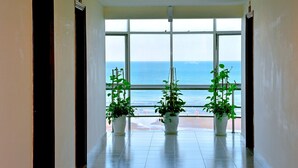 A hallway with large windows and potted plants. - Green Hotel (Ho Chi Minh City)