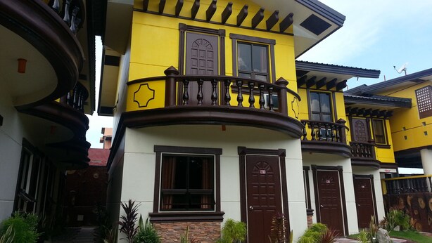 A multi-story building with a yellow facade, multiple balconies, and a stone base. - Costa Villa Beach Resort (San Juan)