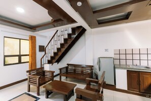 Un intérieur moderne avec un escalier, des meubles en bois, un coin cuisine et une fenêtre avec des rideaux.