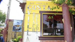 A building with a yellow facade and the words "San Juan, L.U. Costa Vista" on it. - Costa Villa Beach Resort (San Juan)