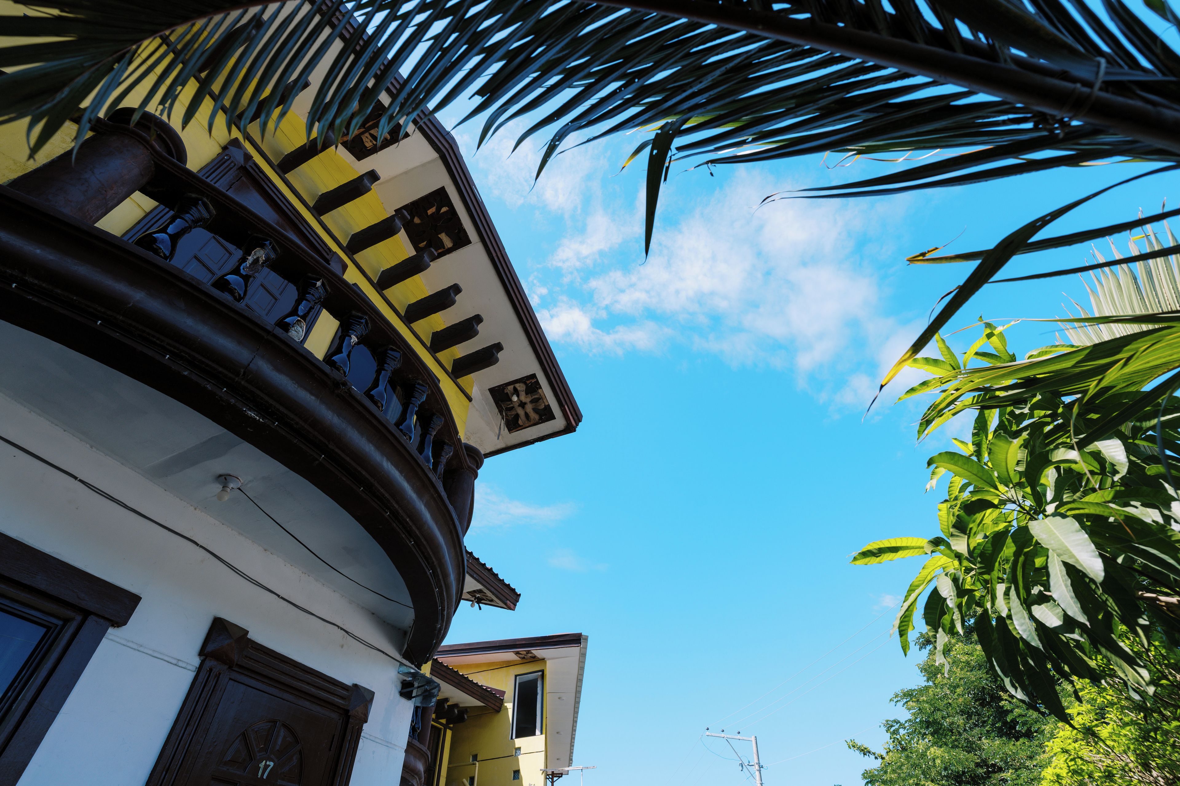 A building with a yellow facade, a black and white striped awning, and a balcony with a railing.