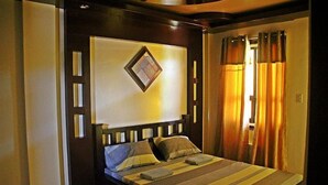 A hotel room with a bed, curtains, and a wall-mounted light fixture. - Costa Villa Beach Resort (San Juan)