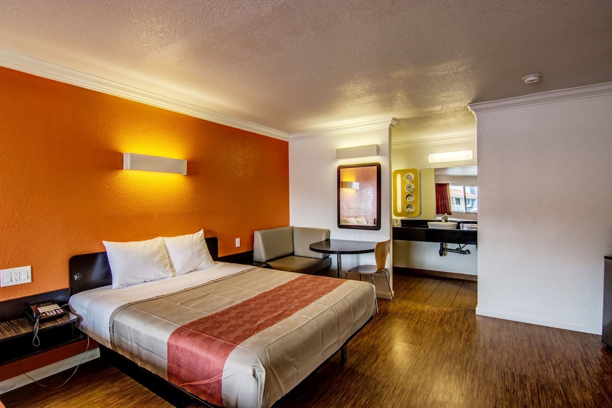 Habitación de hotel con una cama, un escritorio, una silla y una mesita.