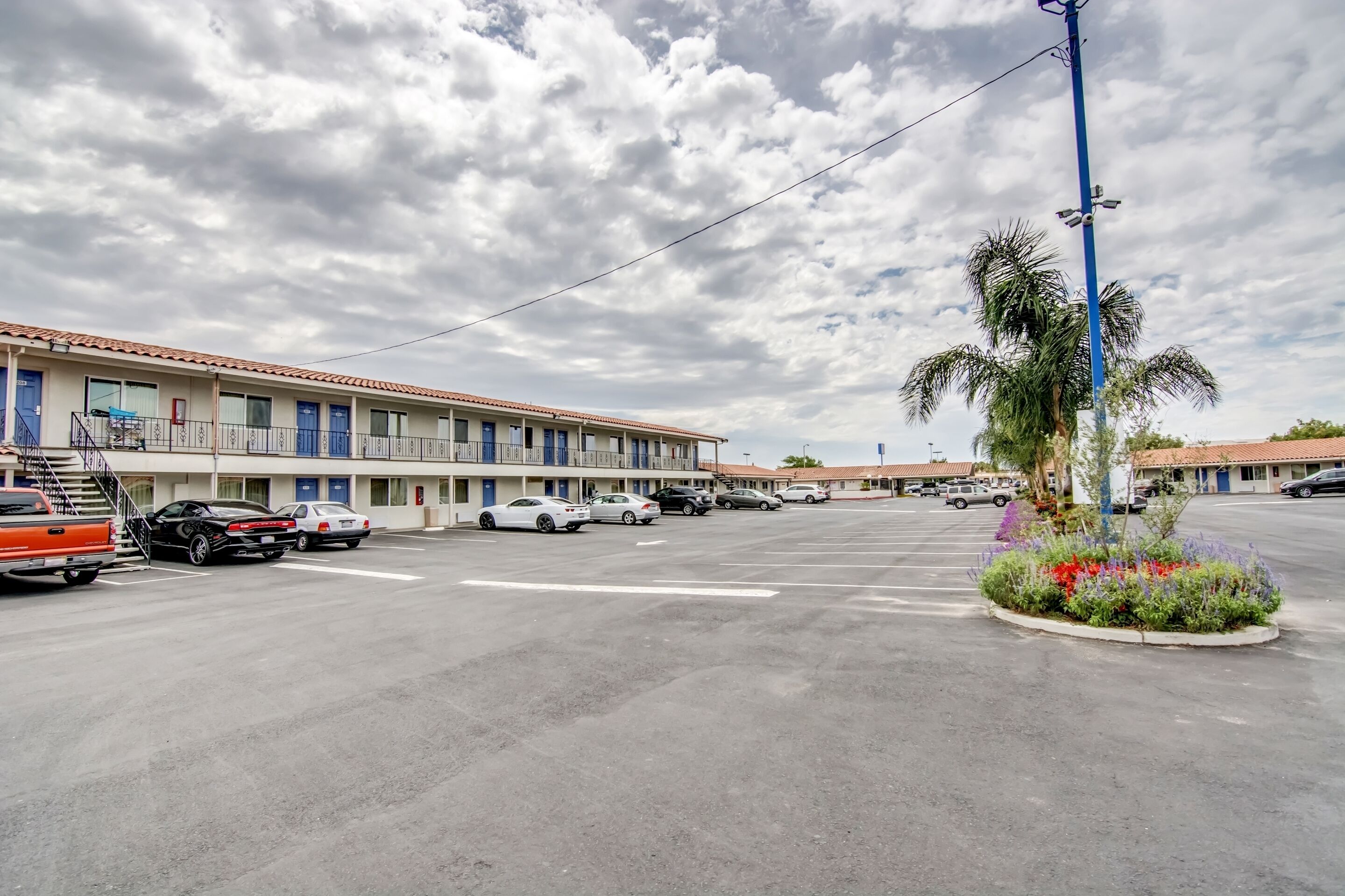 Un motel con varias habitaciones, un estacionamiento y una palmera.