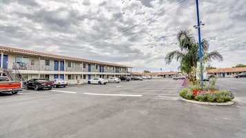Un motel con varias habitaciones, un estacionamiento y una palmera.