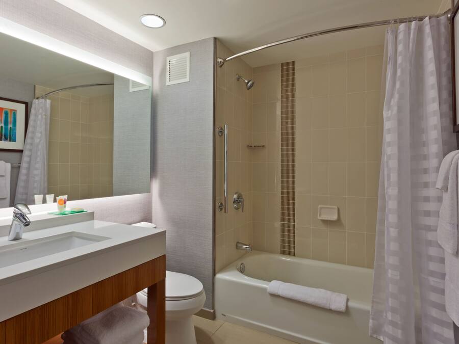A modern bathroom with a glass-enclosed shower, a bathtub, and a vanity with a sink and mirror.