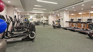 Un gimnasio con diversas máquinas de cardio, equipo de levantamiento de pesas y pelotas de ejercicio.
