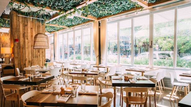 A restaurant with wooden tables and chairs, large windows, and a green vine-covered ceiling. - Hyatt Place Chicago/River North (Chicago)