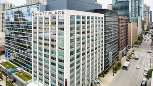 A multi-story hotel with a modern glass facade, located in an urban setting with a parking lot and street views. - Hyatt Place Chicago/River North (Chicago)