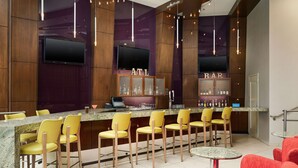 A bar area with a counter, yellow bar stools, and a bar sign. - Hilton Garden Inn Atlanta Midtown (Atlanta)