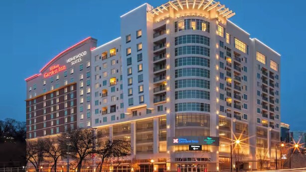 A multi-story hotel with a prominent "Hilton Garden Inn" sign, large windows, and a curved corner design. - Hilton Garden Inn Atlanta Midtown (Atlanta)