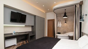 A modern hotel room with a bed, a desk, a flat-screen TV, a shower, and a bathroom with a towel rack. - Komilfo Hotel (Chisinau)