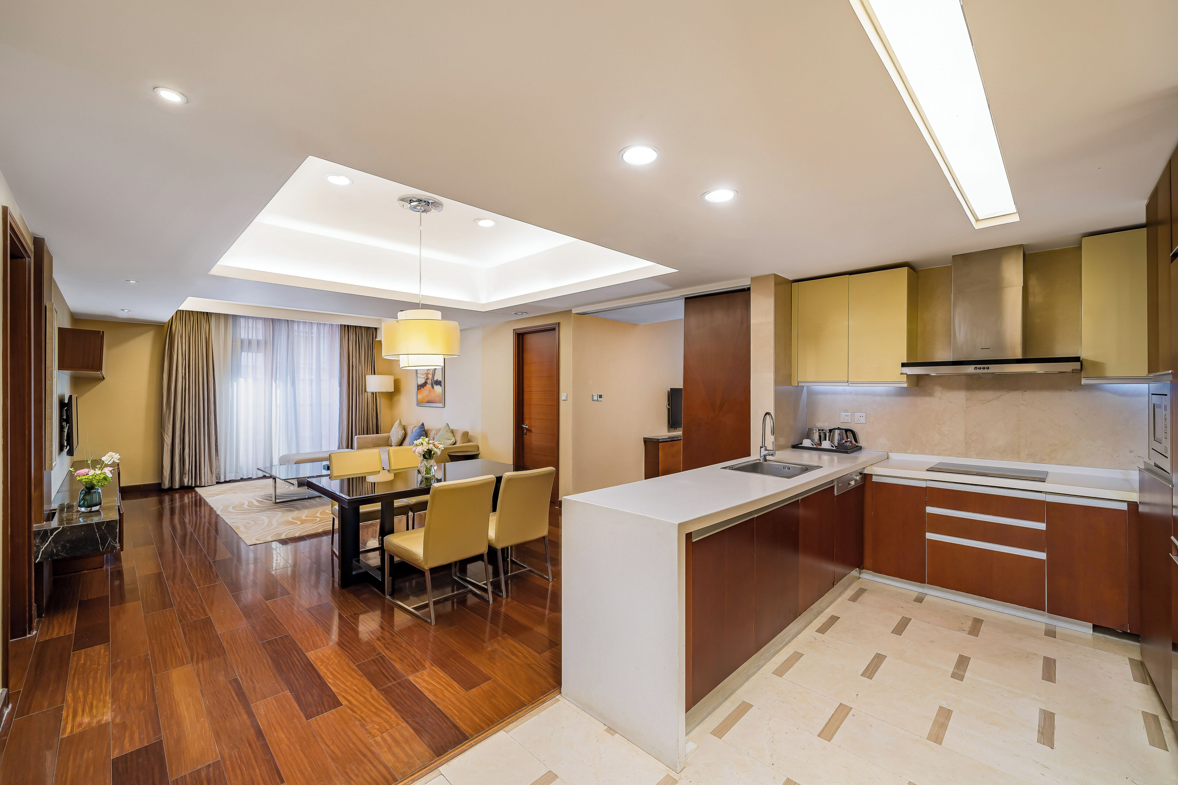 A modern kitchen with a central island, a dining area with a table and chairs, and a living space with a sofa and a lamp.