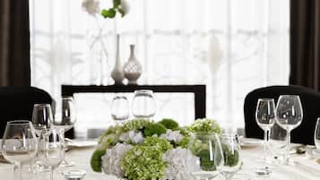 A table set for dining with a centerpiece of white flowers and greenery, clear glassware, and silverware arranged on a tablecloth.