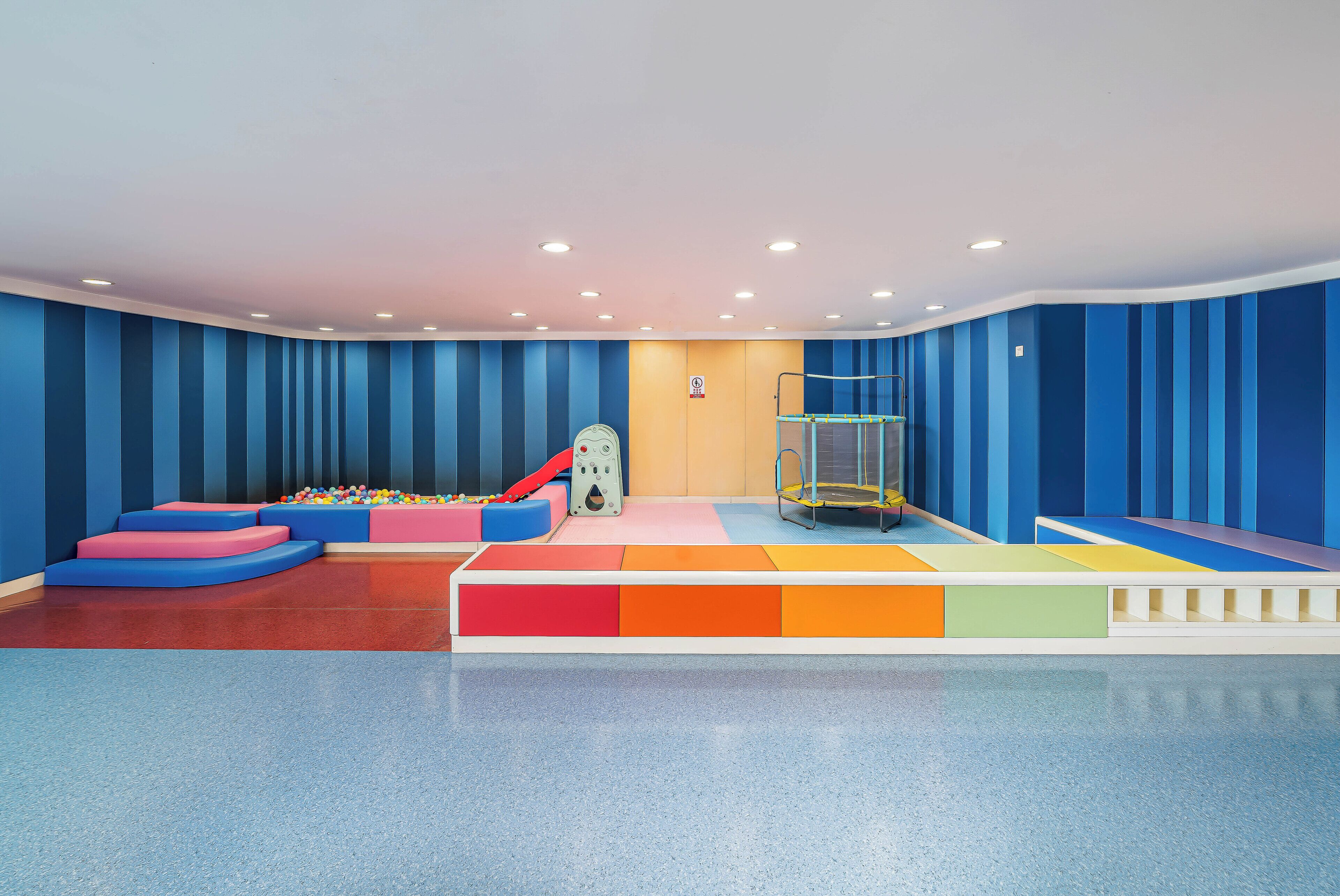 A play area with colorful padded steps, a ball pit, and a trampoline.