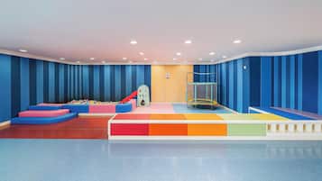 A play area with colorful padded steps, a ball pit, and a trampoline.