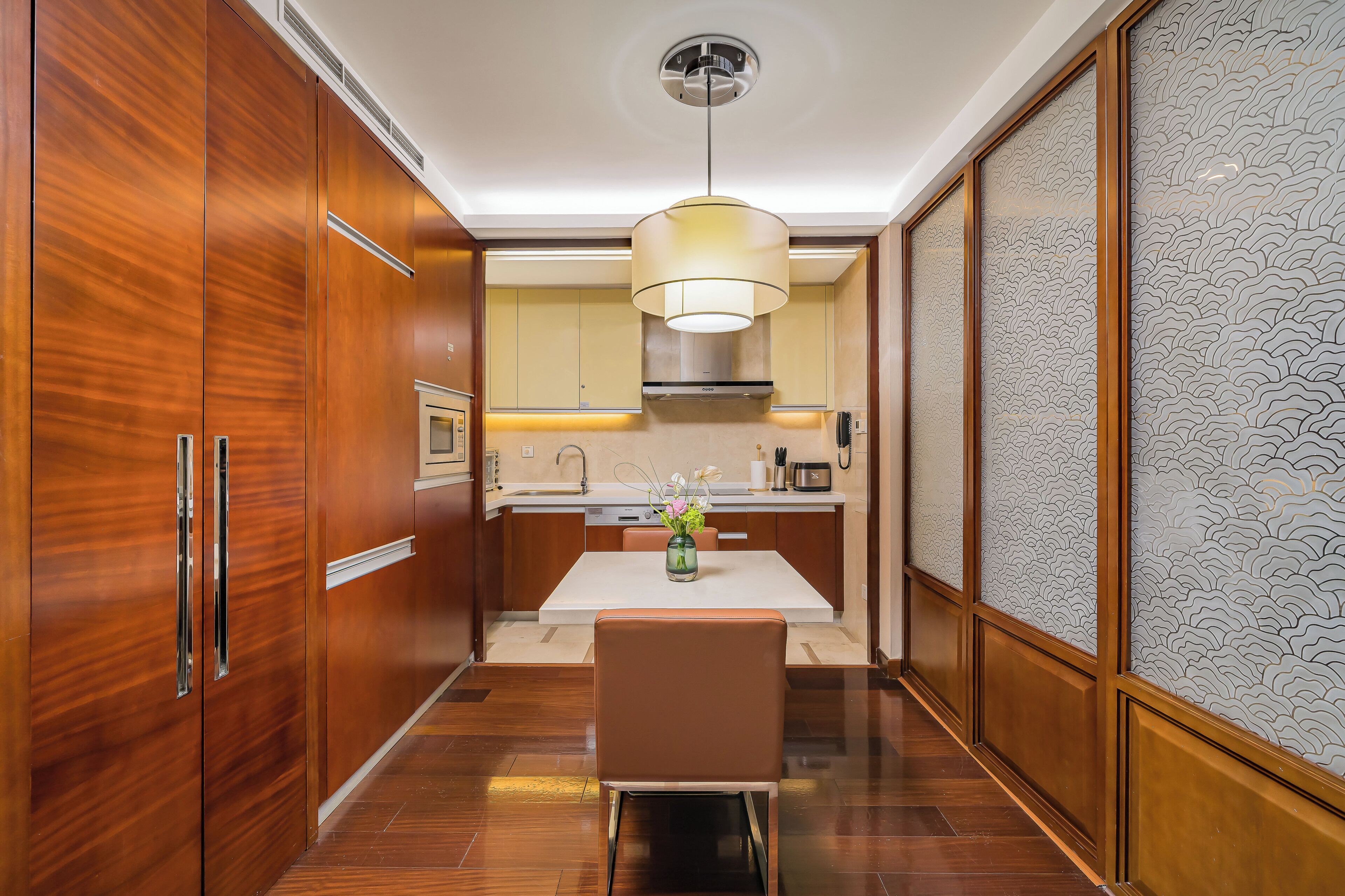 Una cucina moderna con mobili in legno, un'isola centrale e un lampadario a sospensione.