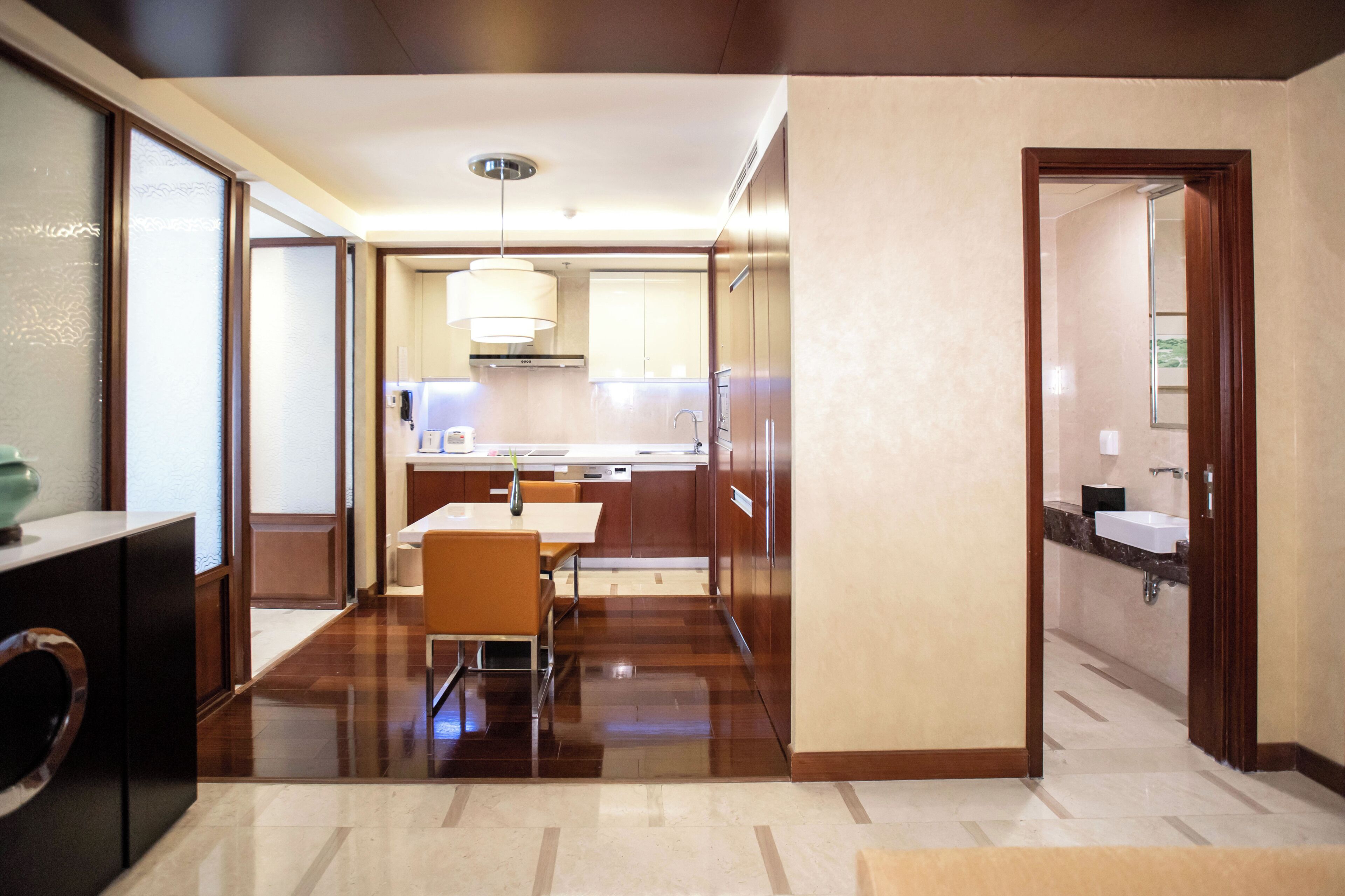 A modern kitchen with a dining area, wooden flooring, and a view into the adjacent living space.