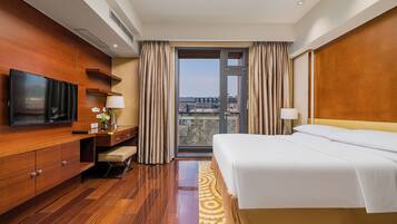 Habitación de hotel con cama, televisor, escritorio y vista a la ciudad.