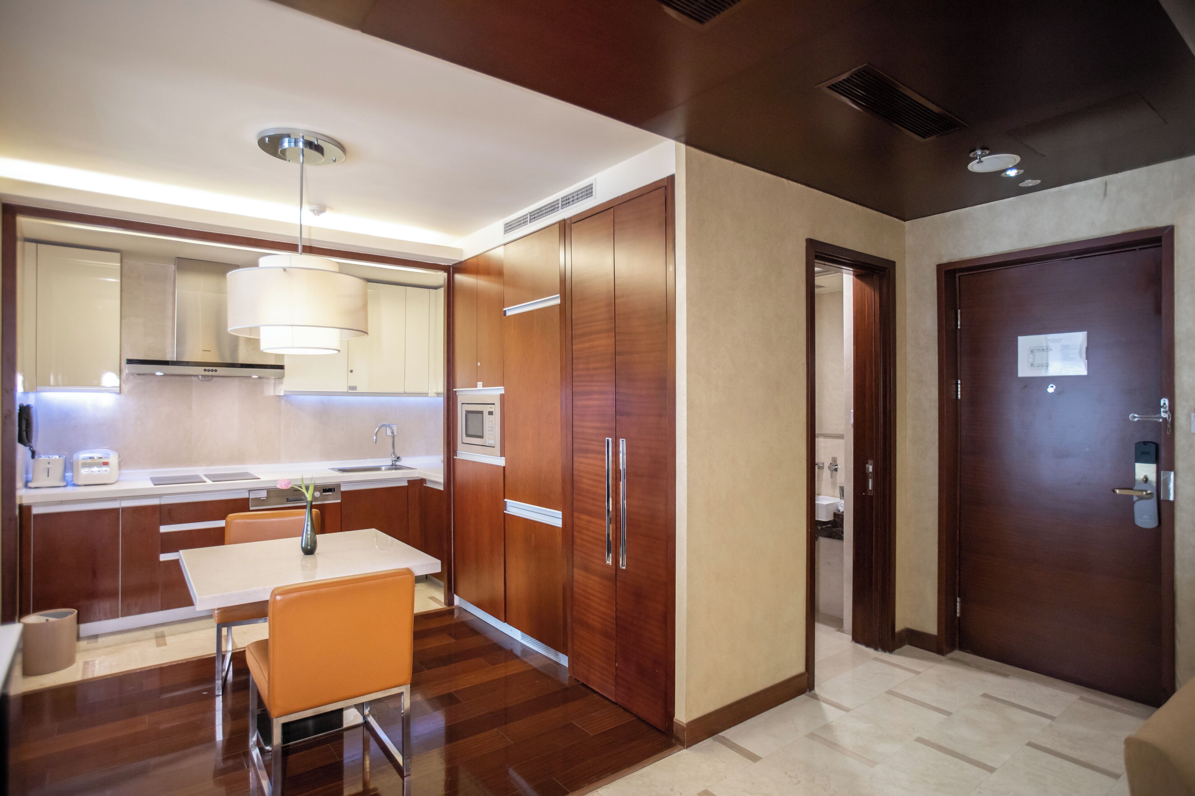 A modern kitchen with wooden cabinets, a dining table, and a microwave.