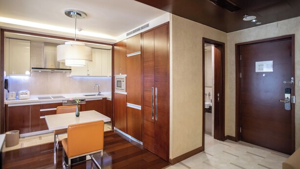 A modern kitchen with wooden cabinets, a dining table, and a microwave. - The Imperial Mansion, Beijing Marriott Executive Apartments (Beijing)