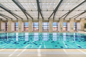 An indoor swimming pool with clear glass walls, large windows, and a tiled floor. - The Imperial Mansion, Beijing Marriott Executive Apartments (Beijing)