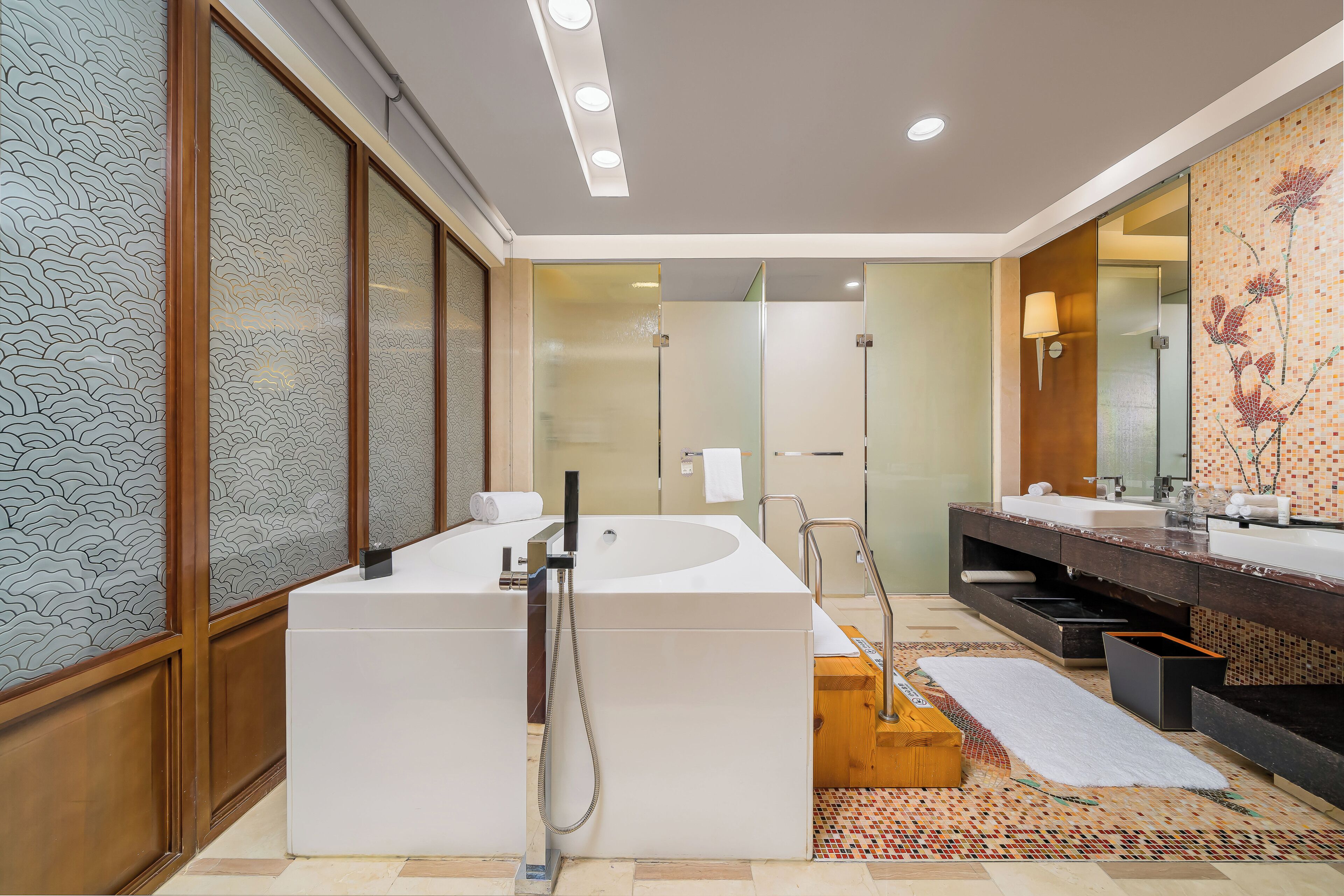 A modern bathroom with a large bathtub, a separate shower area, and a vanity with a mirror.