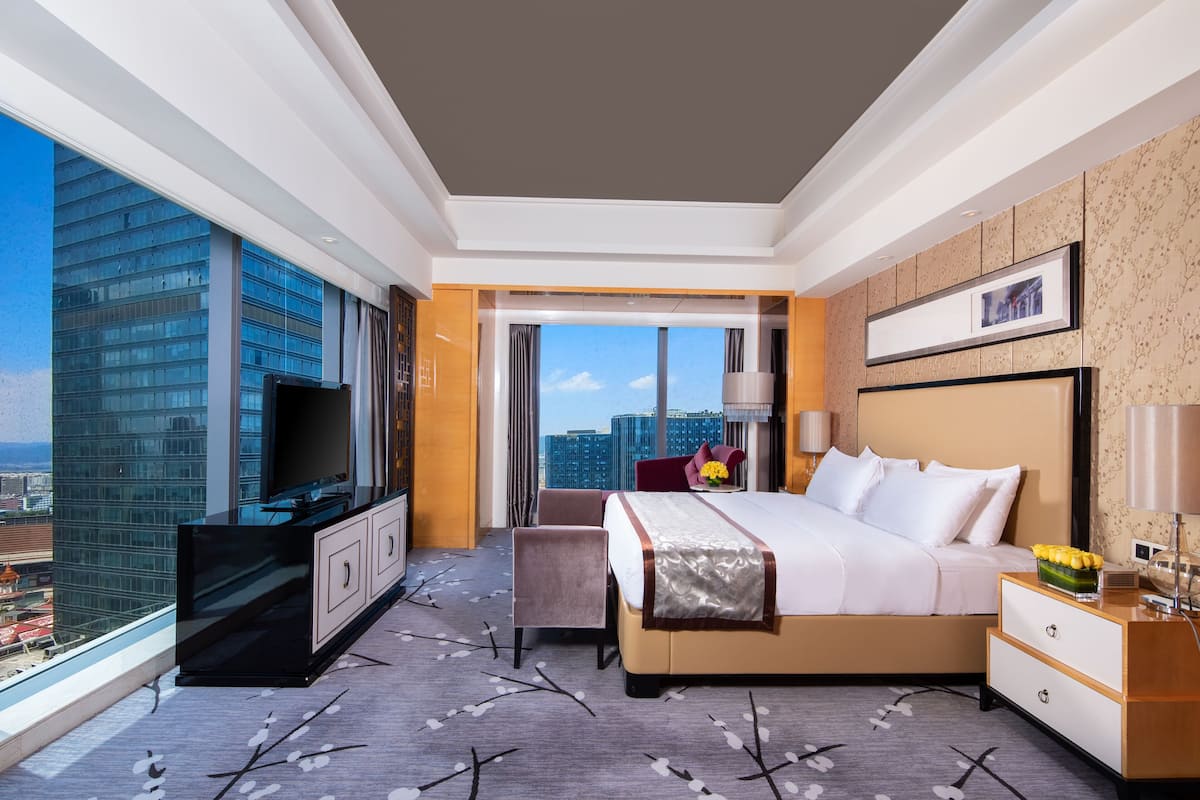 Une chambre d’hôtel moderne dotée d’un grand lit, d’une télévision, d’un bureau et offrant une vue sur le paysage urbain.