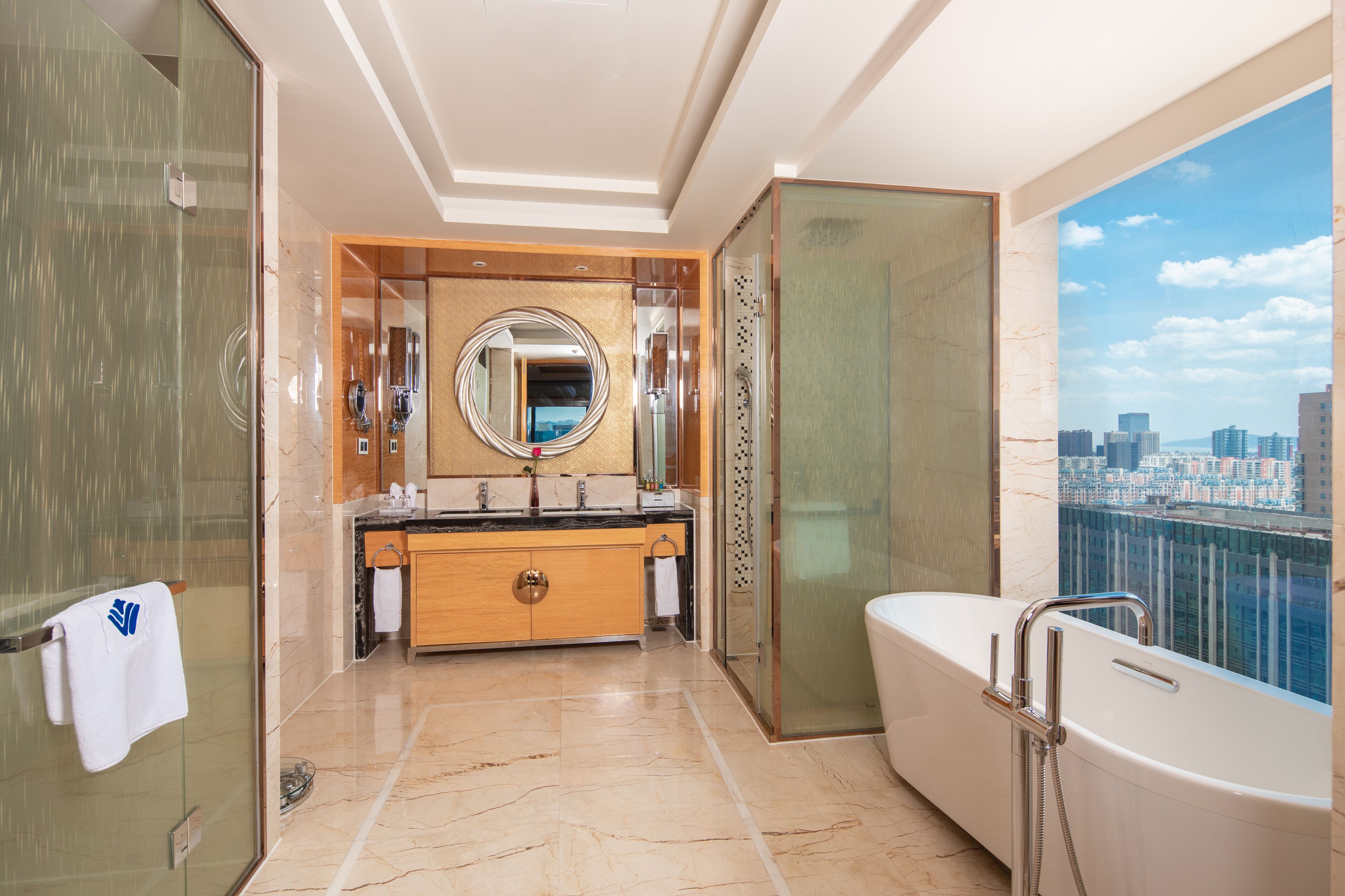 A modern bathroom with a glass-enclosed shower, a large mirror, and a bathtub with a city view.