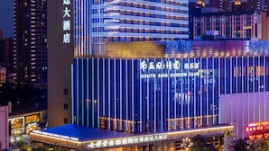 A multi-story hotel with illuminated signage, a prominent entrance, and a view of the surrounding cityscape. - Wyndham Grand Plaza Royale Colorful Yunnan Kunming (Kunming)