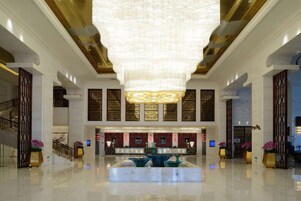 Un'ampia hall con un grande lampadario, una reception e una fontana centrale.