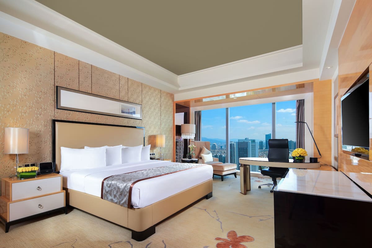 Une chambre d’hôtel avec un grand lit, un bureau et une vue sur la ville.