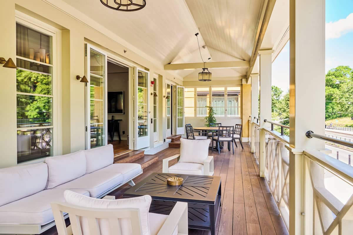 A covered porch with a sofa, chairs, and a dining table.
