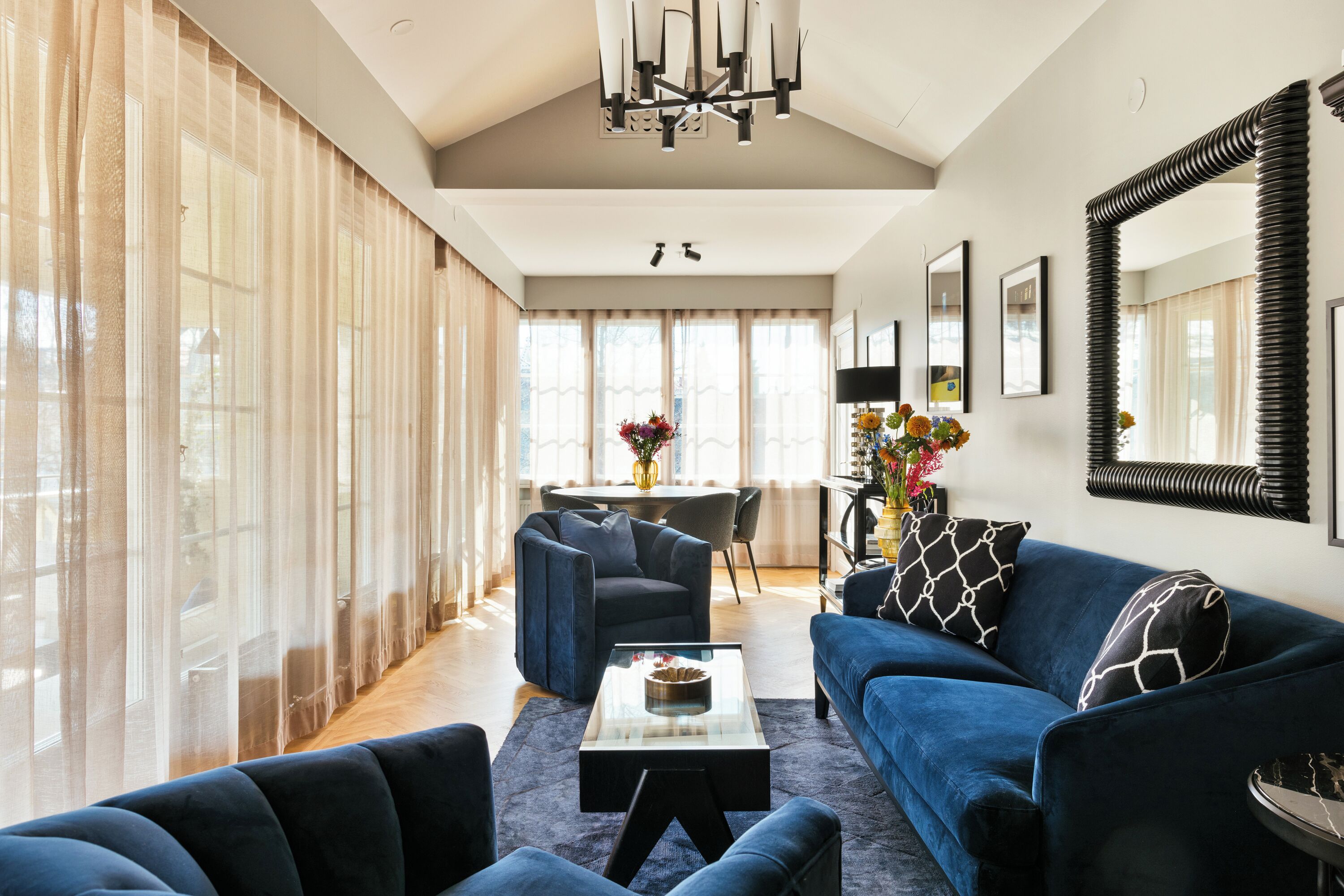 Una sala de estar moderna con un sofá azul, una mesa de centro y un comedor al fondo.