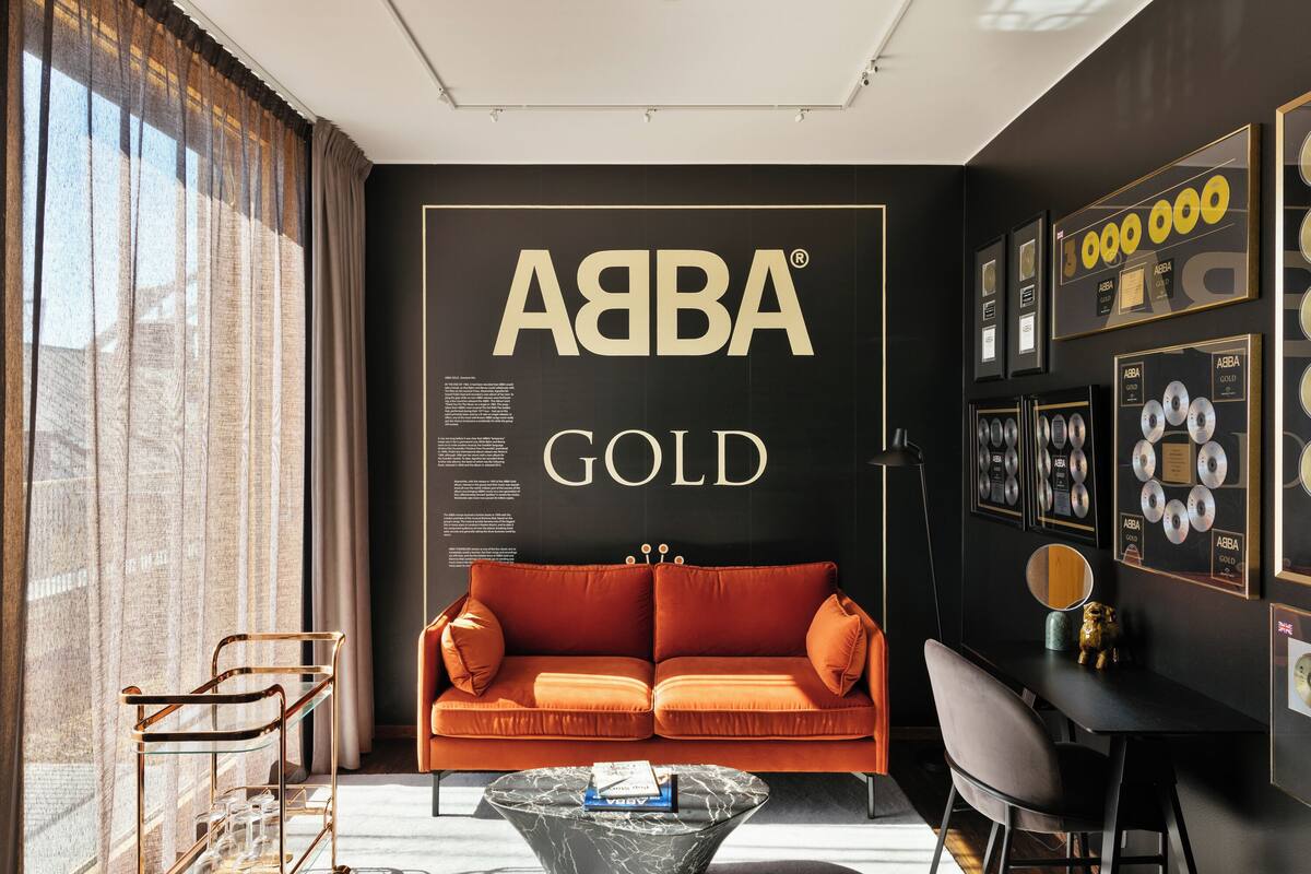 A modern living room with a large wall display reading "ABBA GOLD".