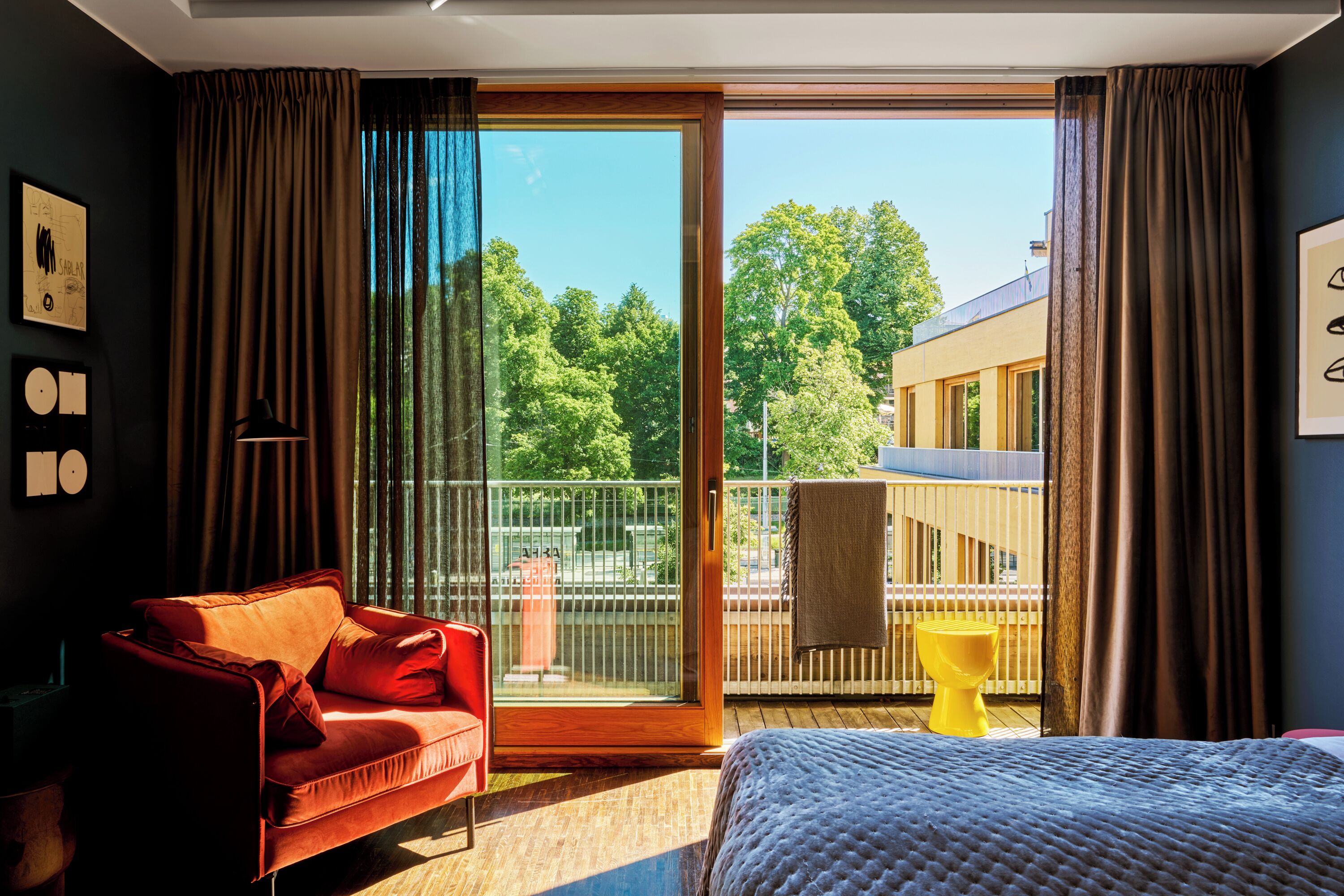 Ein Hotelzimmer mit einem roten Sofa, einem Bett und einer großen Schiebeglasdoor, die auf einen Balkon führt.